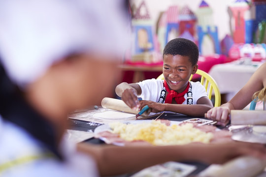 Children dressed up as pirates using rolling pin