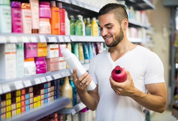 Man selecting shampoo in the store.