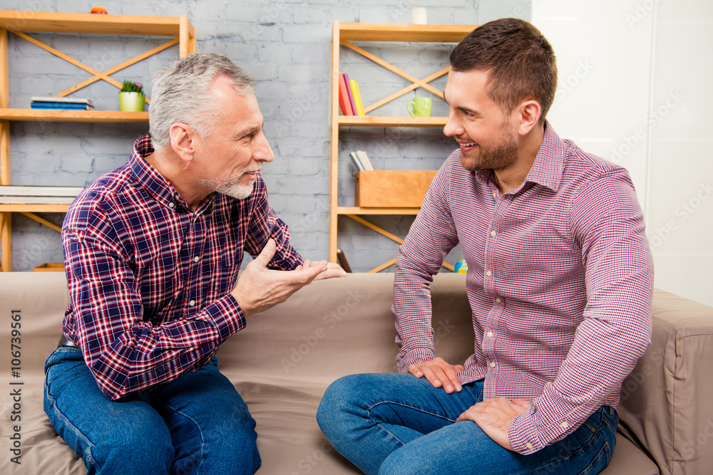 Poster conversation of two handsome adult man sitting on sofa