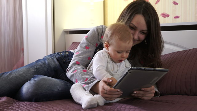 The girl with the tablet and the child on a bed.