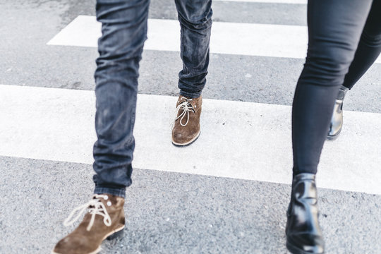Legs of man and woman walking on crosswalk