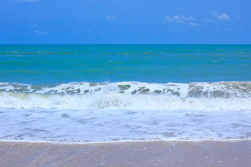 A tranquil sea scene and gravel beach. The sky above is a perfect blue color.  Outdoors.
