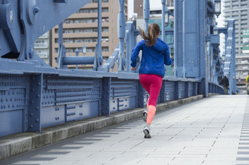 Back figure of a woman running on the bridge