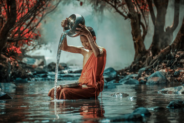 Little monk taking a bath at waterfall, Nong Khai, Thailand. - obrazy, fototapety, plakaty