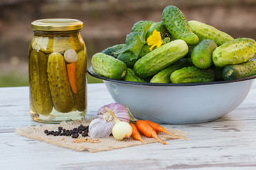 Cucumbers in metal bowl, vegetables and spices for pickling and jar pickled cucumbers