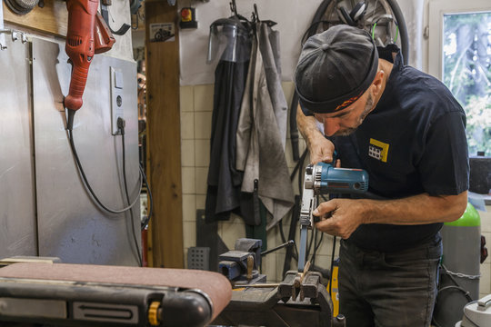 Knife maker in workshop at work - Powered by Adobe