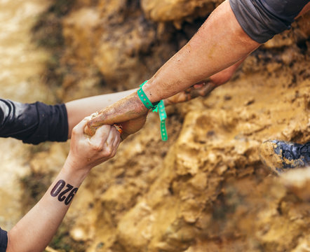 Participants in extreme obstacle race helping each other - Powered by Adobe