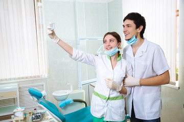 Obraz premium Dentists woman and a man doing photo selfie in the dental office