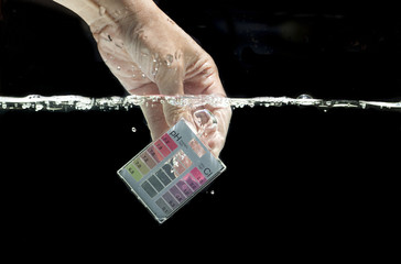 Mini water testing kit dipping in clear water with black background