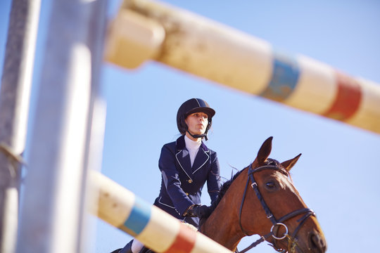 Young woman on horse approaching obstacle on course