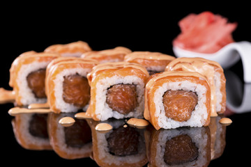 Sushi Roll with salmon over  black background with reflection