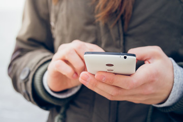 Girl in the green jacket uses a smartphone while walking on the