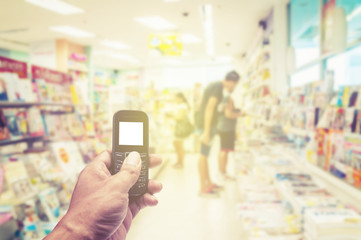 Fototapeta na wymiar Phone white screen in hand on blurred book store