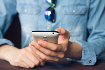 Woman using a mobile phone, she is dressed in a denim shirt and