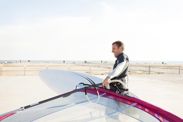Smiling man at the coast holding surfboard