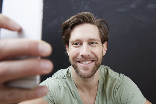Portrait of smiling young man taking a selfie with smartphone