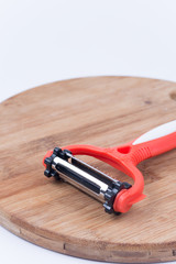 Fruit and vegetables plastic peeler on the kitchen woden board