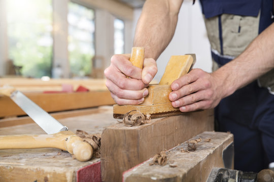 Carpenter planing wood in workshop