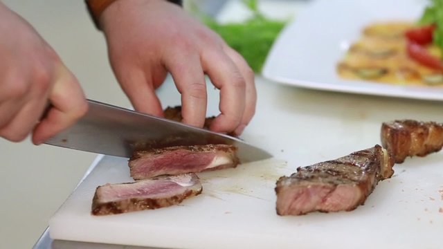 Man slicing meat with a knife on a chopping board