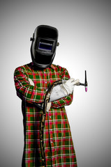 welder with tungsten torch and wleding mask wears square shirt