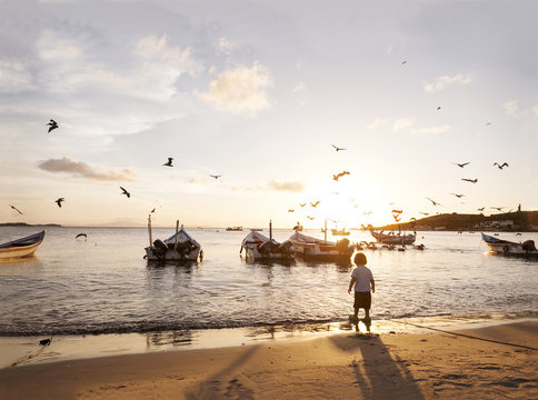 Venezuela, Isla Margarita, Juan Griego, back view of little boy standing at seafront by sunset