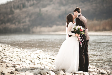 Fototapeta na wymiar Happy newlyweds, bride and groom posing on river with beautiful views