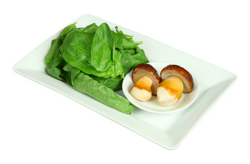 Fresh boletus mushrooms and spinach on white plate. Isolated on