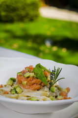 pasta with salmon served on white plate on green background