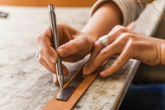 Woman cutting elastic fabric rubber band in saddlery