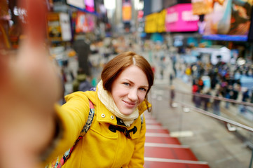 Beautiful young woman taking a selfie with her smartphone on Times Square