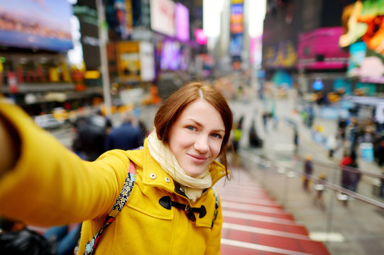 Beautiful young woman taking a selfie with her smartphone on Times Square
