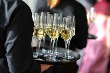 Waitress holding a dish of champagne and wine glasses
