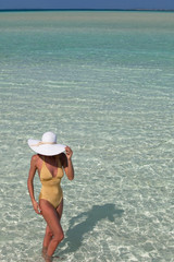 Fototapeta na wymiar femme avec un chapeau blanc dans l'eau de mer transparente