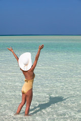 femme avec un chapeau blanc dans l'eau de mer transparente