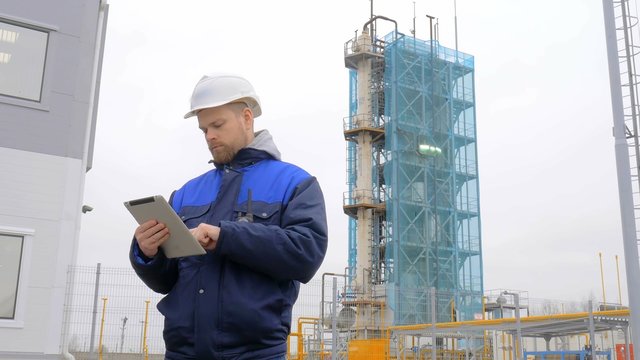 engineer holding a tablet, talking on the radio, smiling and looking at the camera at the factory