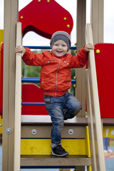 Little boy playing on the playground in the autumn park