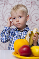Fototapeta na wymiar Beautiful little baby boy eats banana