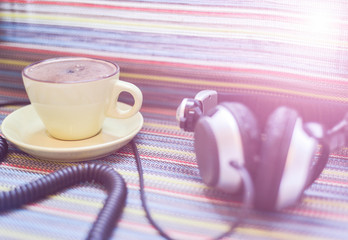 headphones and cup with coffee on the colorful tablecloth