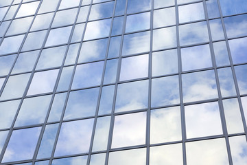 Fototapeta premium modern glass building with reflections of blue sky and clouds