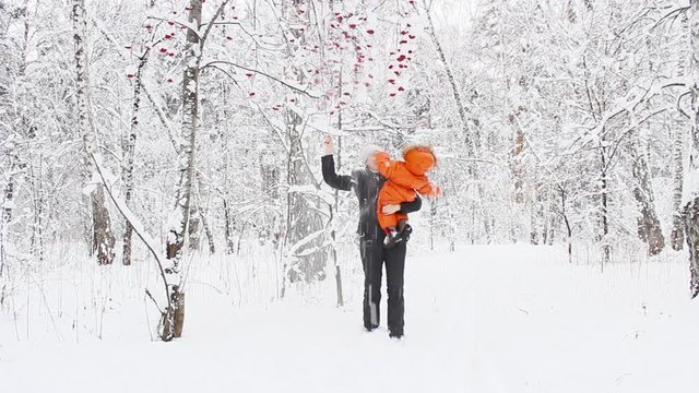 Mom plays with the baby in the winter in the forest