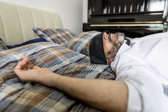 Businessman lying on his bed with tie covering his eyes