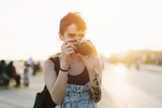 USA, New York, Coney Island, young woman taking photos at sunset