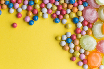 Candies colorful mix on yellow bright background with copy space