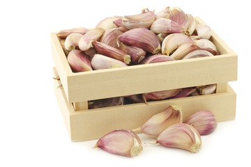 dried garlic cloves in a wooden box on a white background

