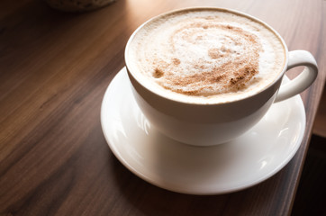 Cup of cappuccino on wooden table in cafeteria