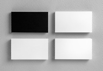 Blank black and white business cards on gray background. Mockup for branding identity. Template for graphic designers portfolios. Top view.