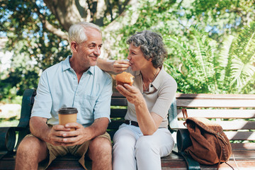 Loving senior couple sitting on a park bench - Powered by Adobe