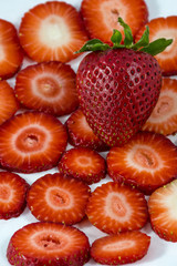 Big strawberry lies on sliced strawberries