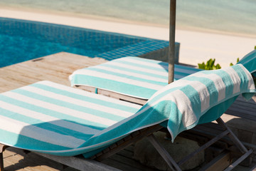 parasol and sunbeds by sea on maldives beach