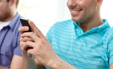 close up of happy friends with smartphones at home